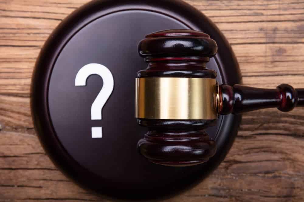 Question Mark Sign With Gavel Over Wooden Texture Background