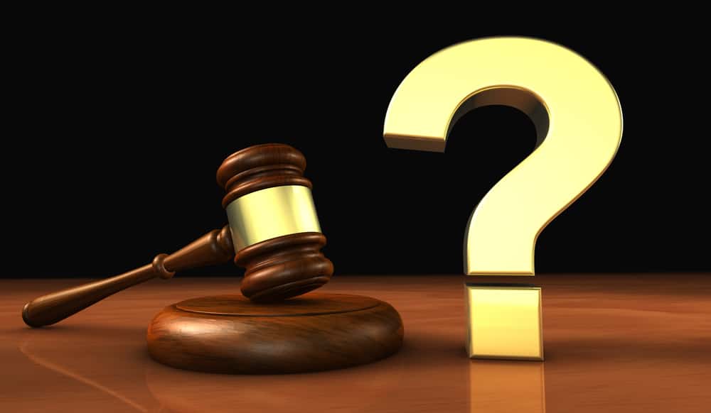 A golden question mark symbol and a wooden judge gavel.
