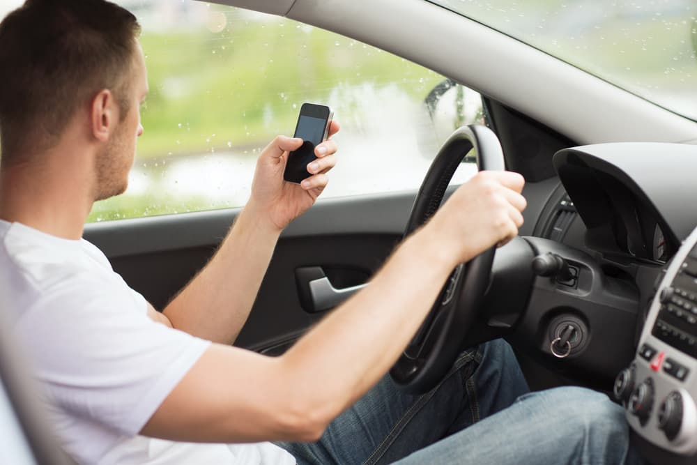 Transportation and vehicle concept – a man using his phone while driving.